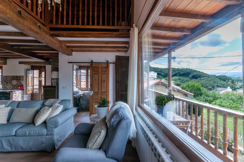 Zona de estar de La Casina de Gallegos con grandes ventanas y vistas al paisaje